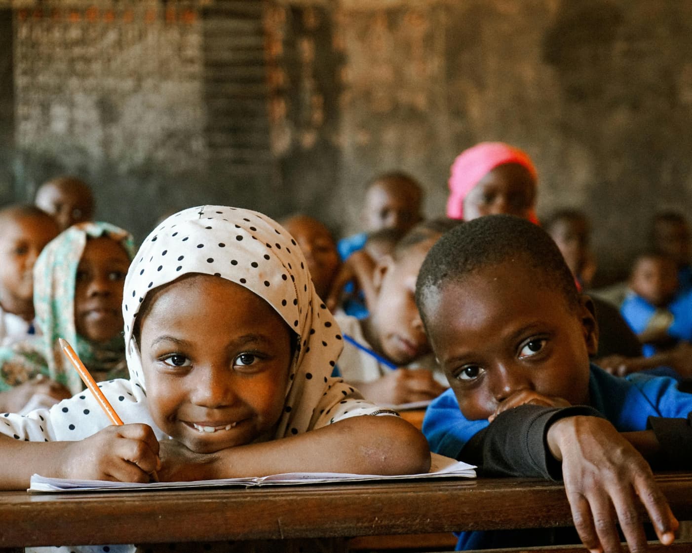 Girl in hijab at school desk — focused, determined, full of potential