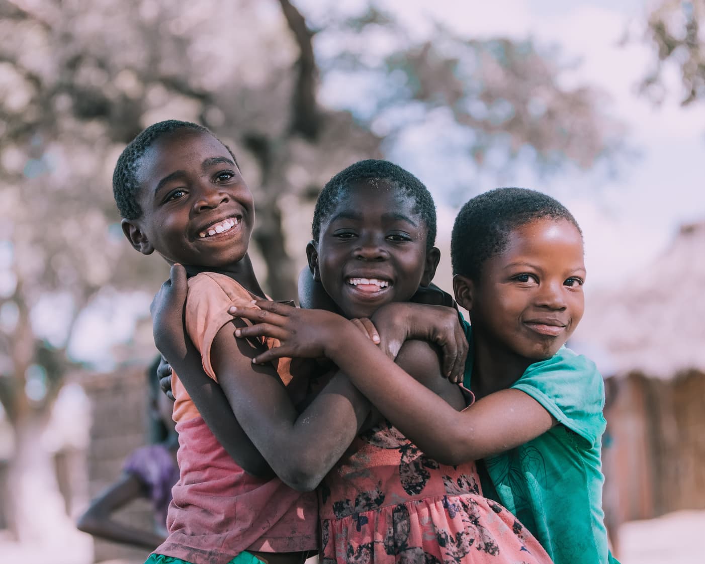 Three children hugging and laughing — joy, safety and community