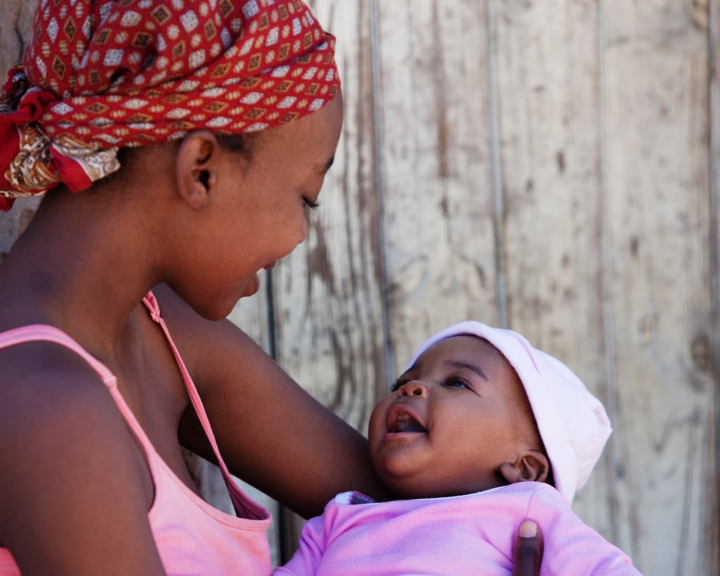 Young mother in red headwrap holding smiling baby
